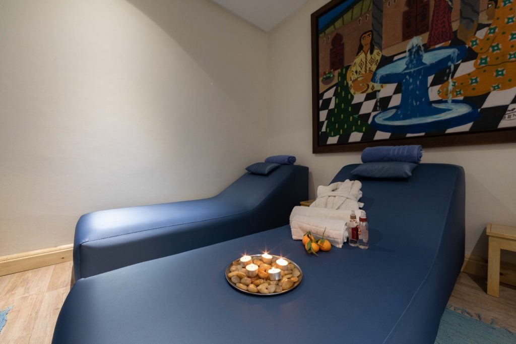 Salle de massage double avec deux tables et des peignoirs